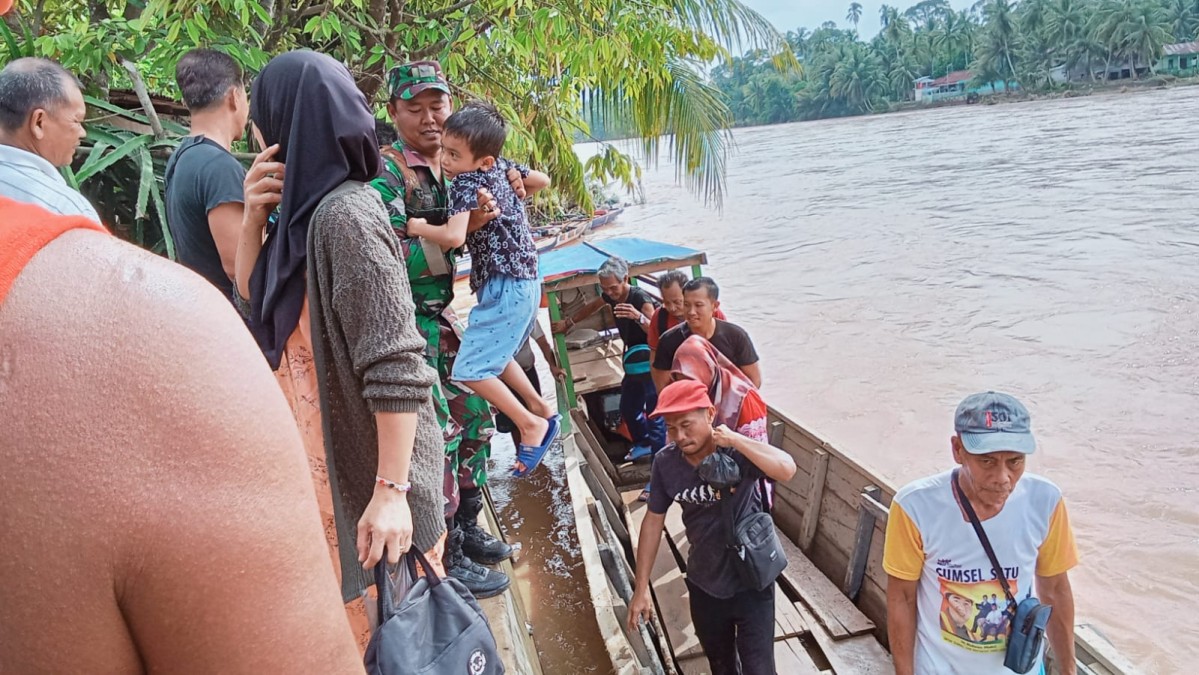 Babinsa Koramil 406-01/Rawas ulu serda Niki sudoyo membantu warga menyebrangi sungai didesa binaan.