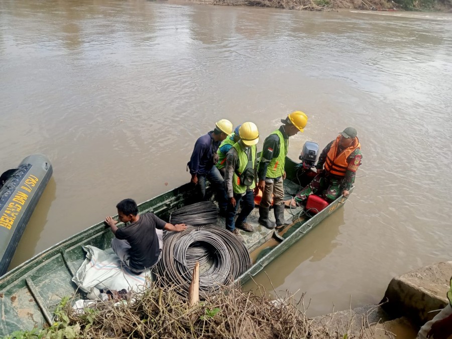 Anggota Koramil 406-03/rupit membantu personil PLN menyebrangi sungai, untuk perbaikan listrik di desa