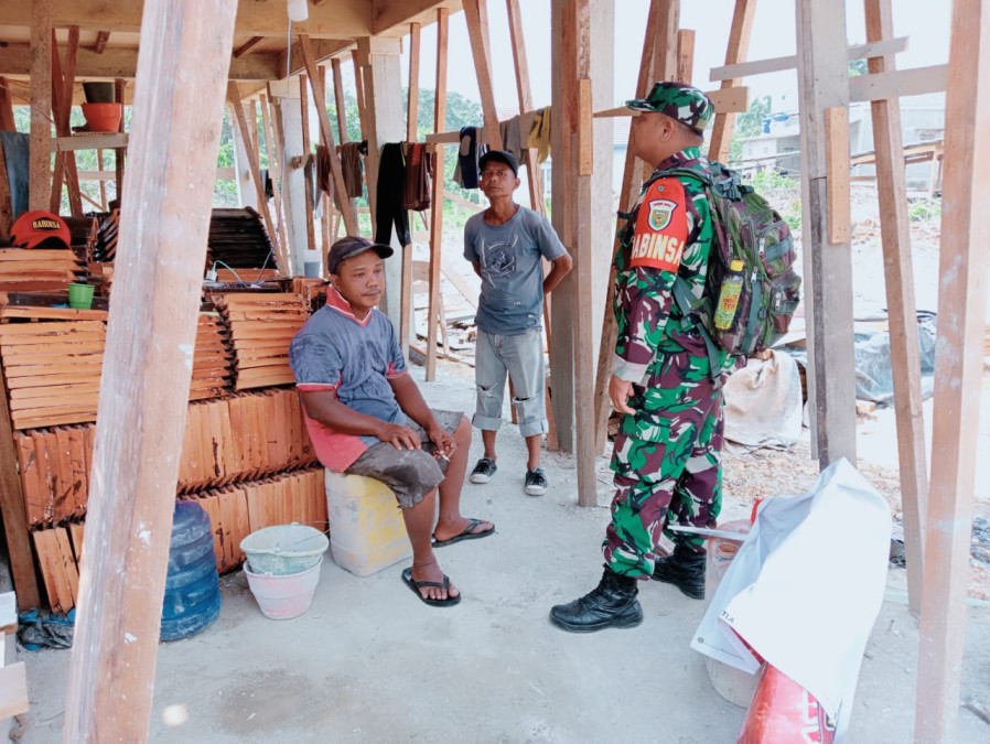 Babinsa menyapa para pekerja bangunan dan bersamaan melaksanakan kegiatan Komsos Dengan para pekerja